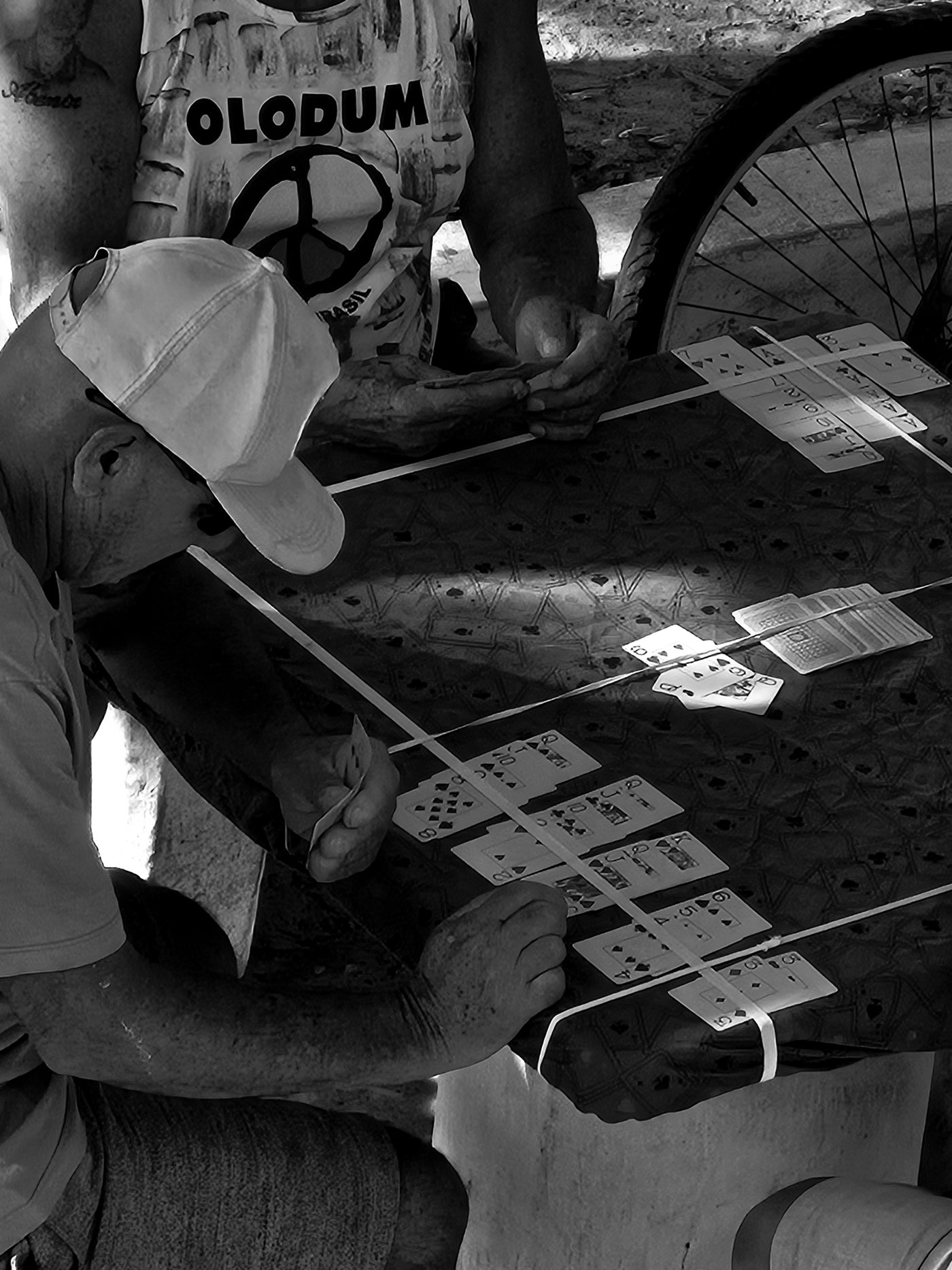 Fotografia de Paulo Ricardo Santos: homens reunidos em volta de uma mesa jogando cartas, em preto e branco